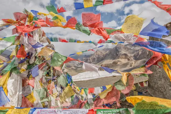 Close view of prayer flags moving in the wind above the mountains